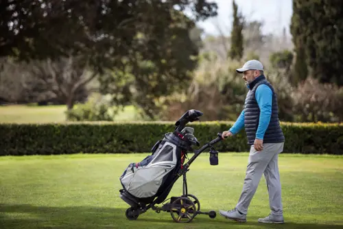 golfer pushing electric golf trolley
